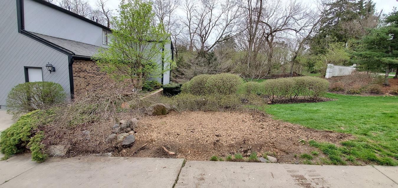 There is a large pile of mulch in front of a house.