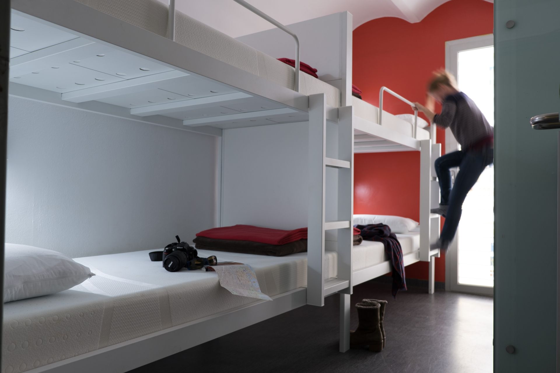 A person is climbing up a bunk bed in a dorm room