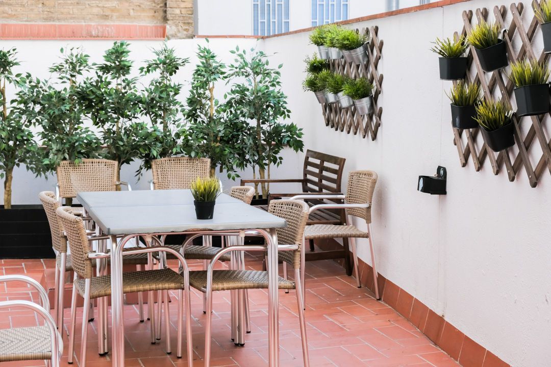 A patio with a table and chairs and plants on the wall.