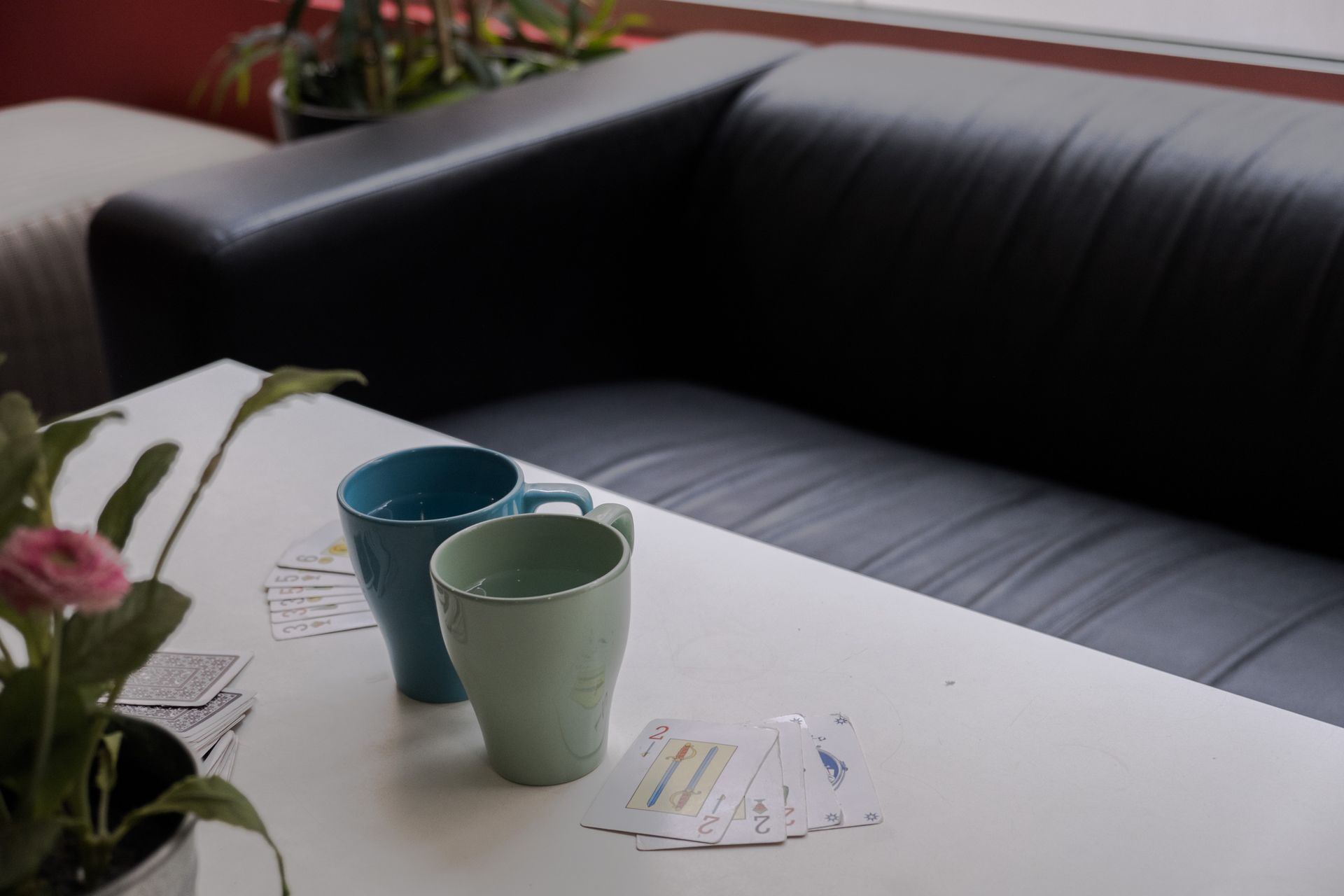 Tres tazas y cartas sobre una mesa frente a un sofá.