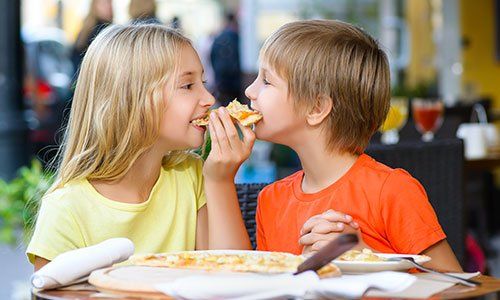 Bambini felici che mangiano pizza sorridente