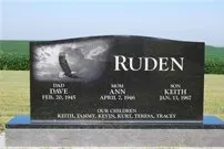 A black gravestone with a picture of an eagle on it in a cemetery.