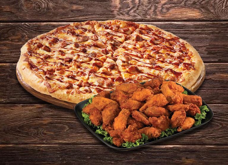 Pizza with barbecue sauce and a tray of fried chicken wings on a wooden surface.
