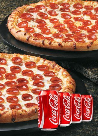 Two pepperoni pizzas on a black tray with four Coca-Cola cans.