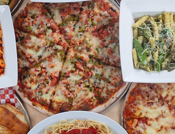 Overhead view: pizza, pasta dishes, and bread on a table.