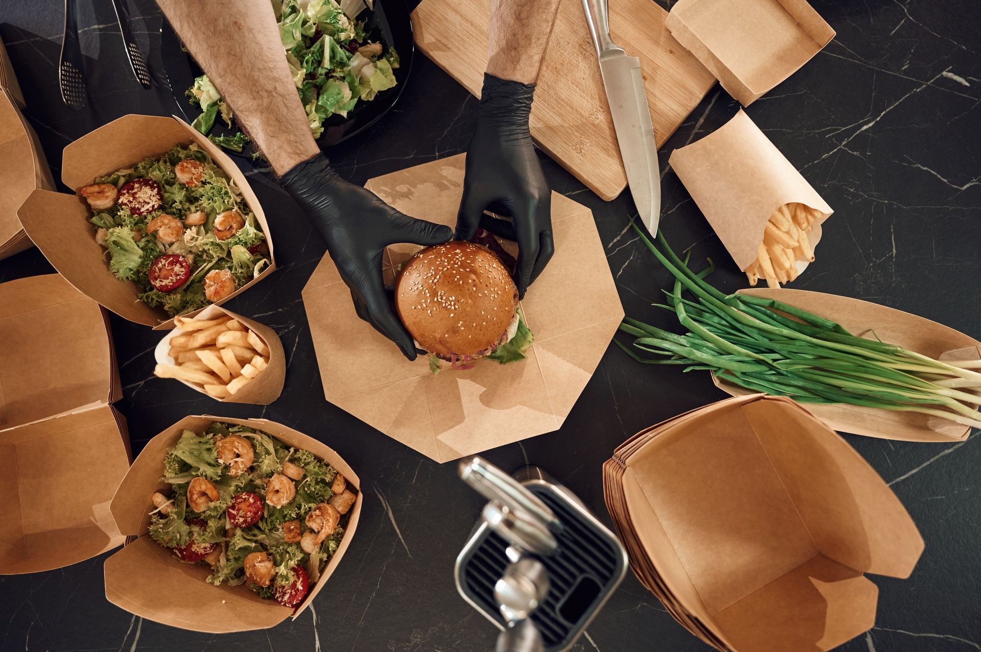 A person is wrapping a hamburger in brown paper.
