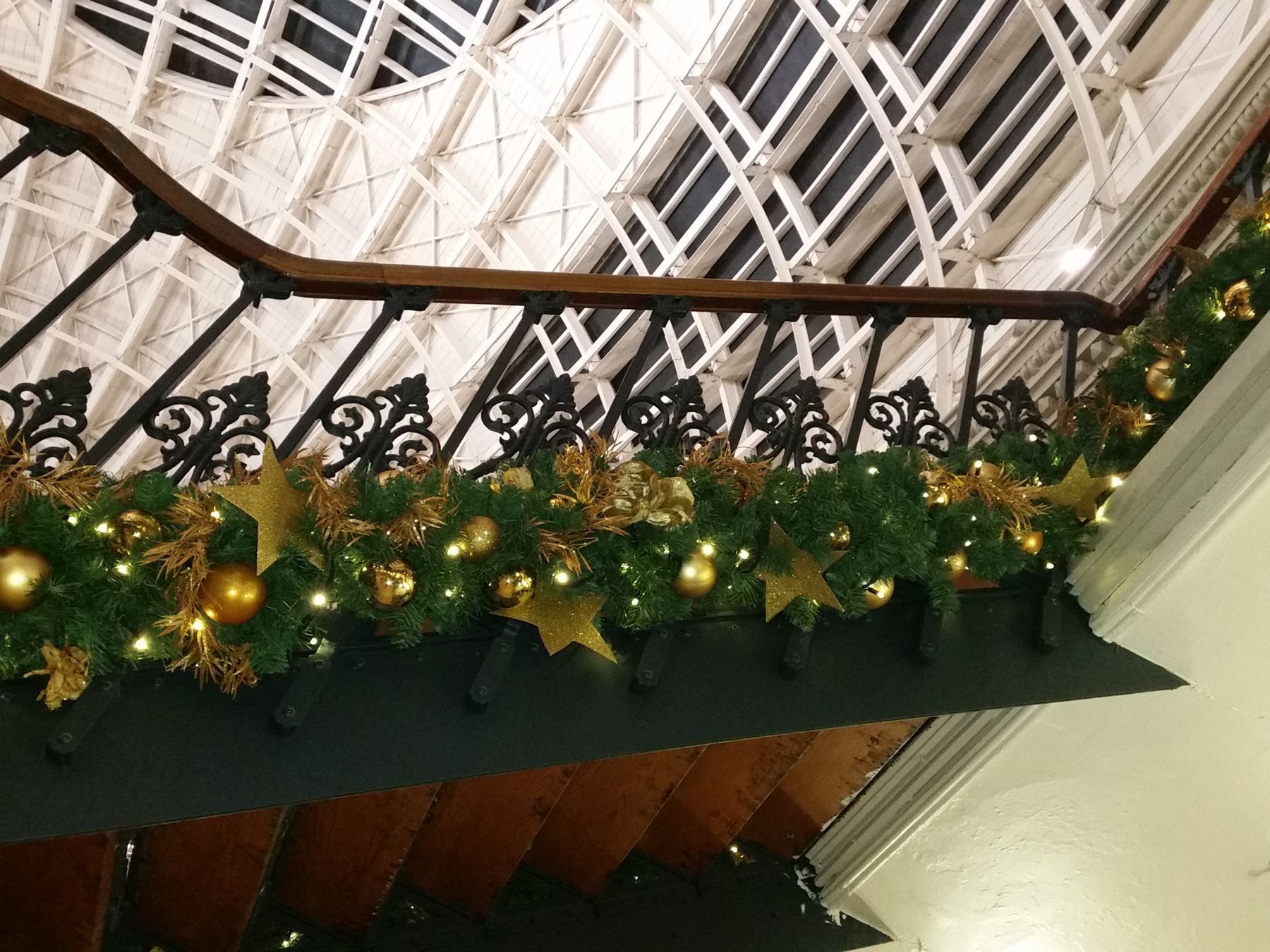 A staircase with christmas decorations on the railing.
