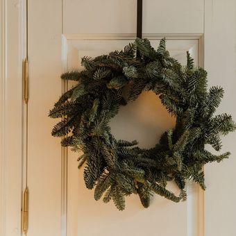 A christmas wreath is hanging on a white door.