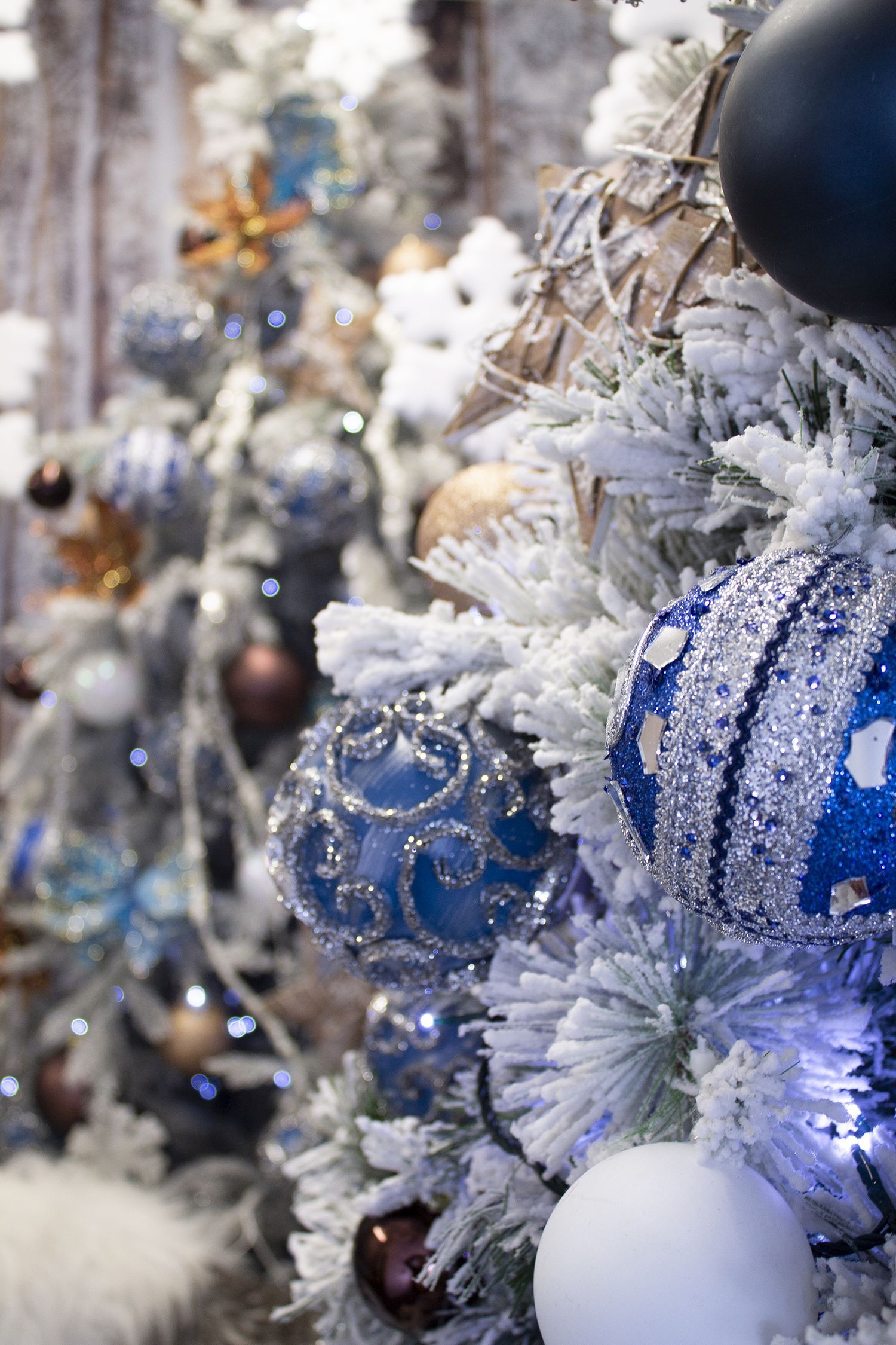A close up of a christmas tree with blue and white decorations.
