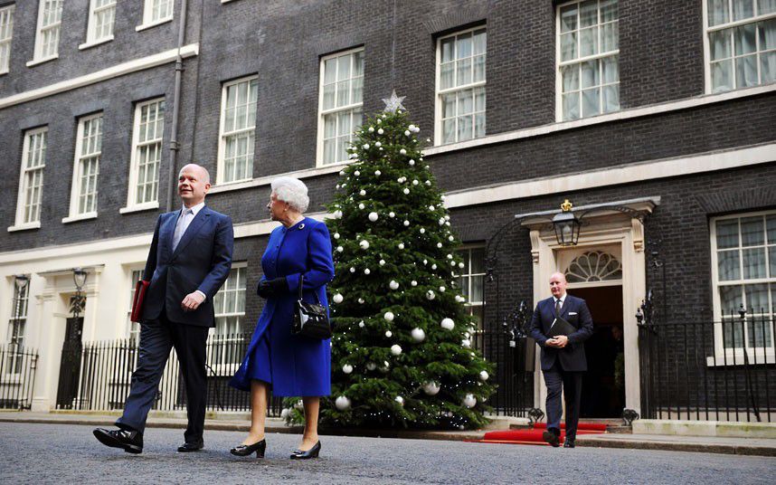 A man and a woman are walking in front of a christmas tree.