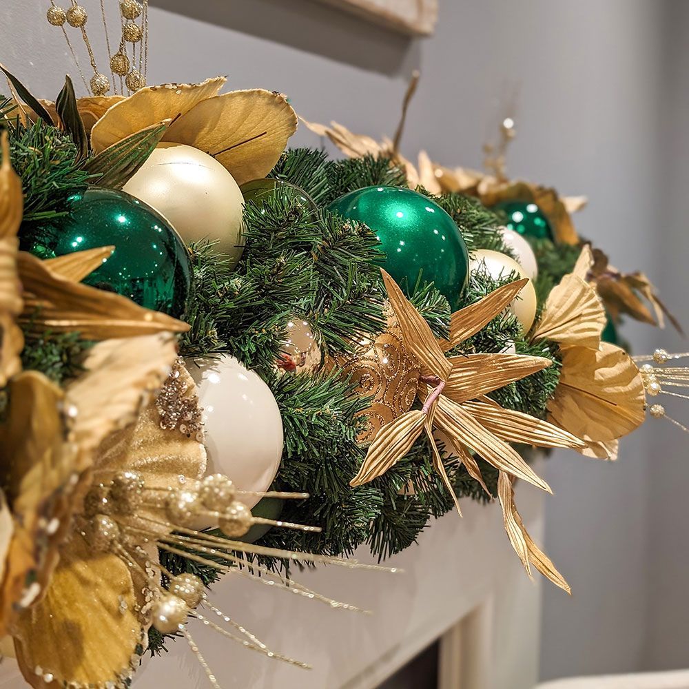 A mantle decorated with green and gold christmas decorations.