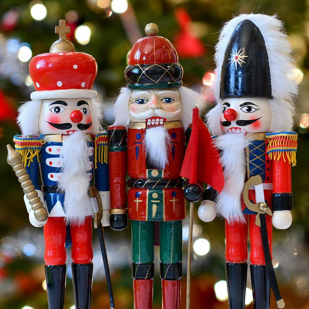 Three nutcrackers are standing in front of a christmas tree.