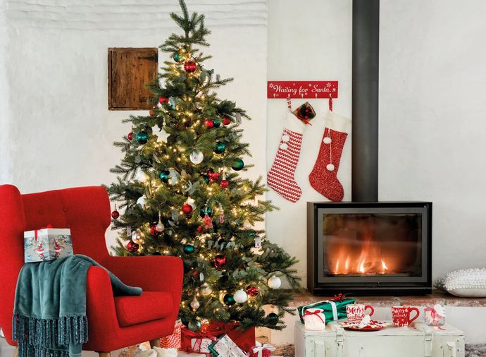 A living room with a christmas tree and a fireplace.