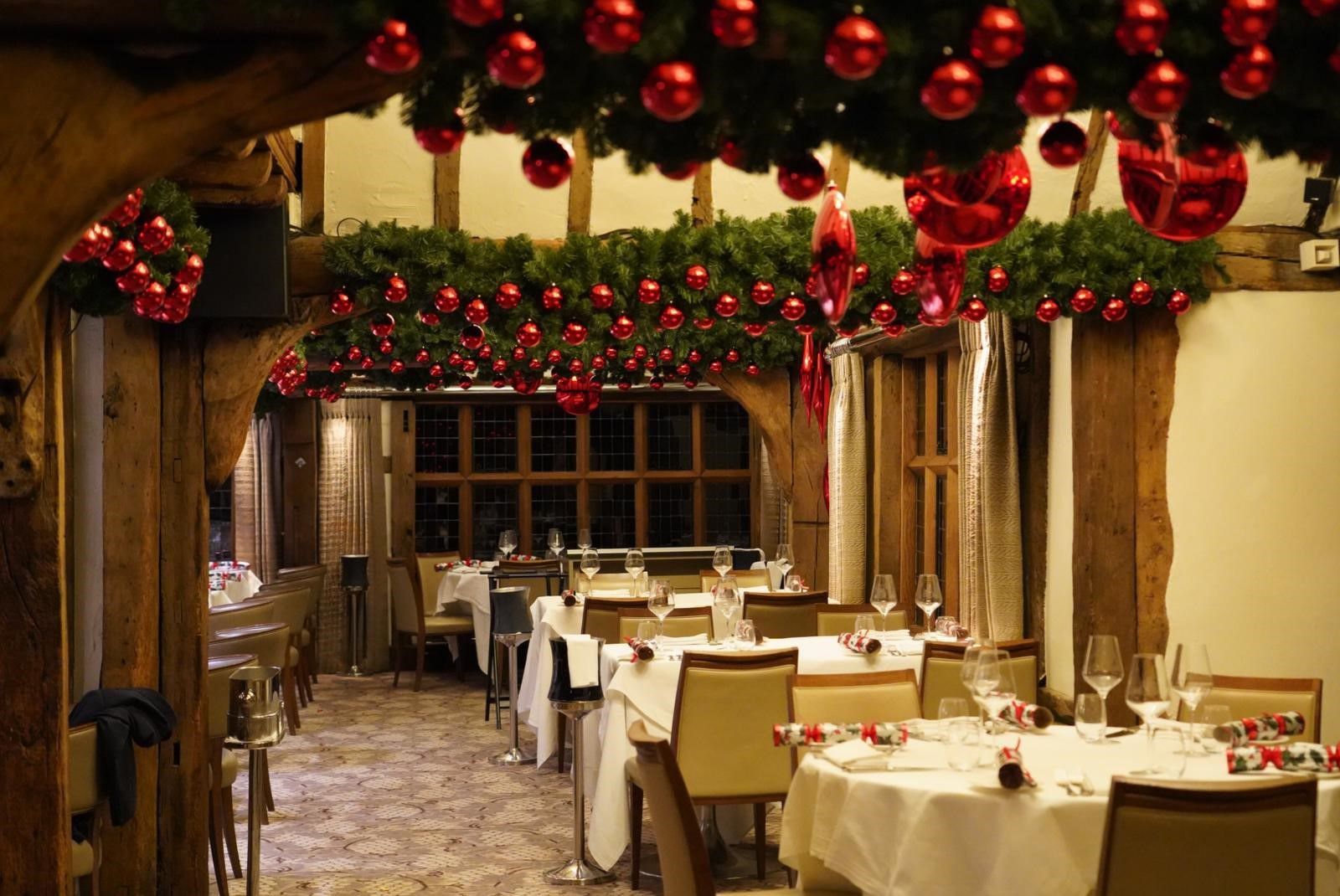 A restaurant filled with tables and chairs decorated for christmas.