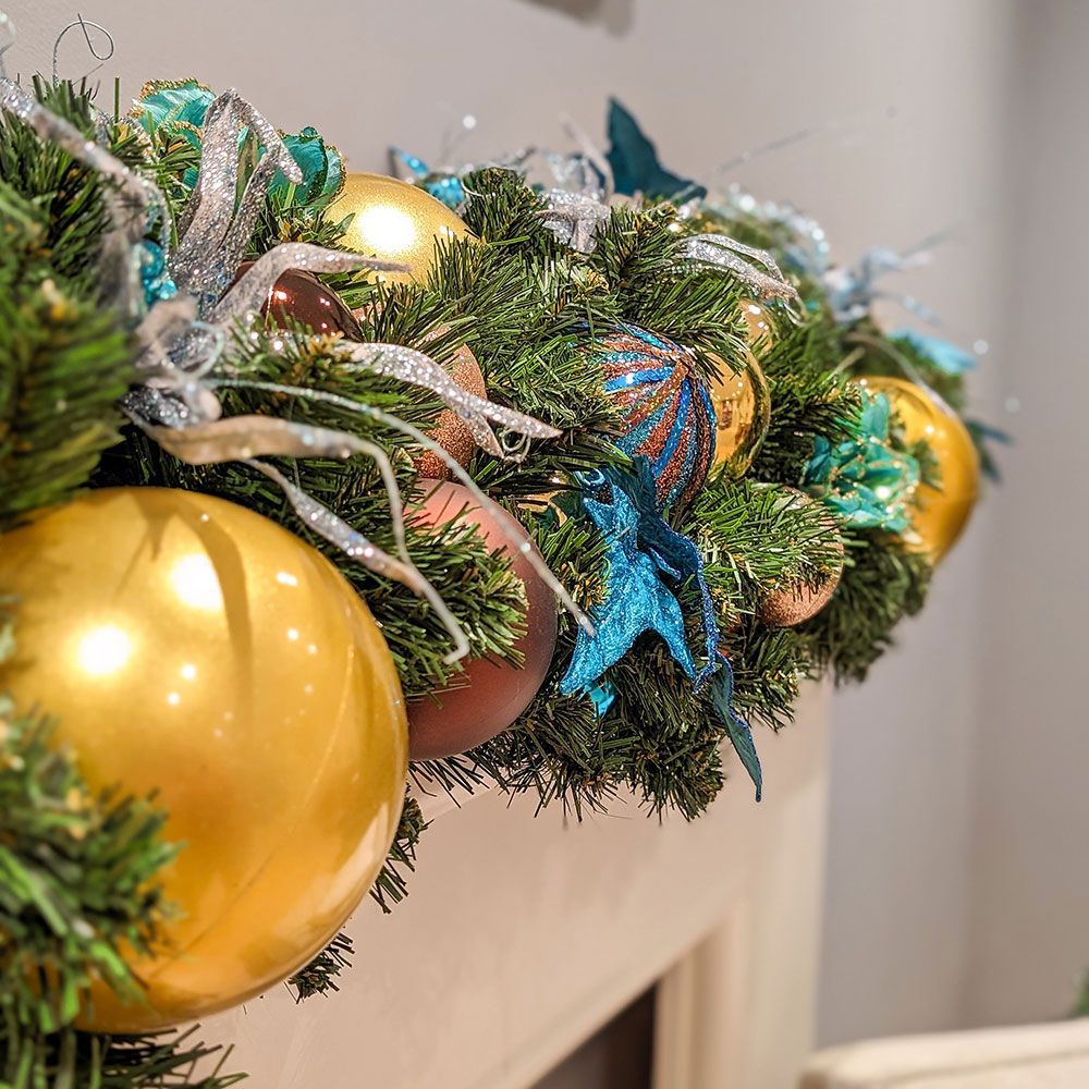 A christmas garland with gold balls and blue starfish on a mantle.