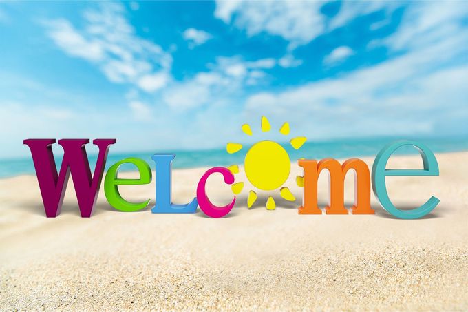 The word welcome is on a beach with a sun in the background