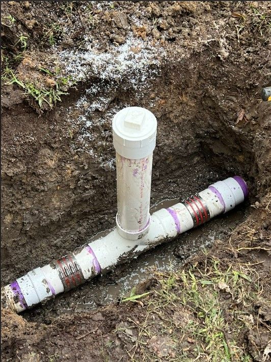 A pvc pipe is sitting in the dirt in a hole.