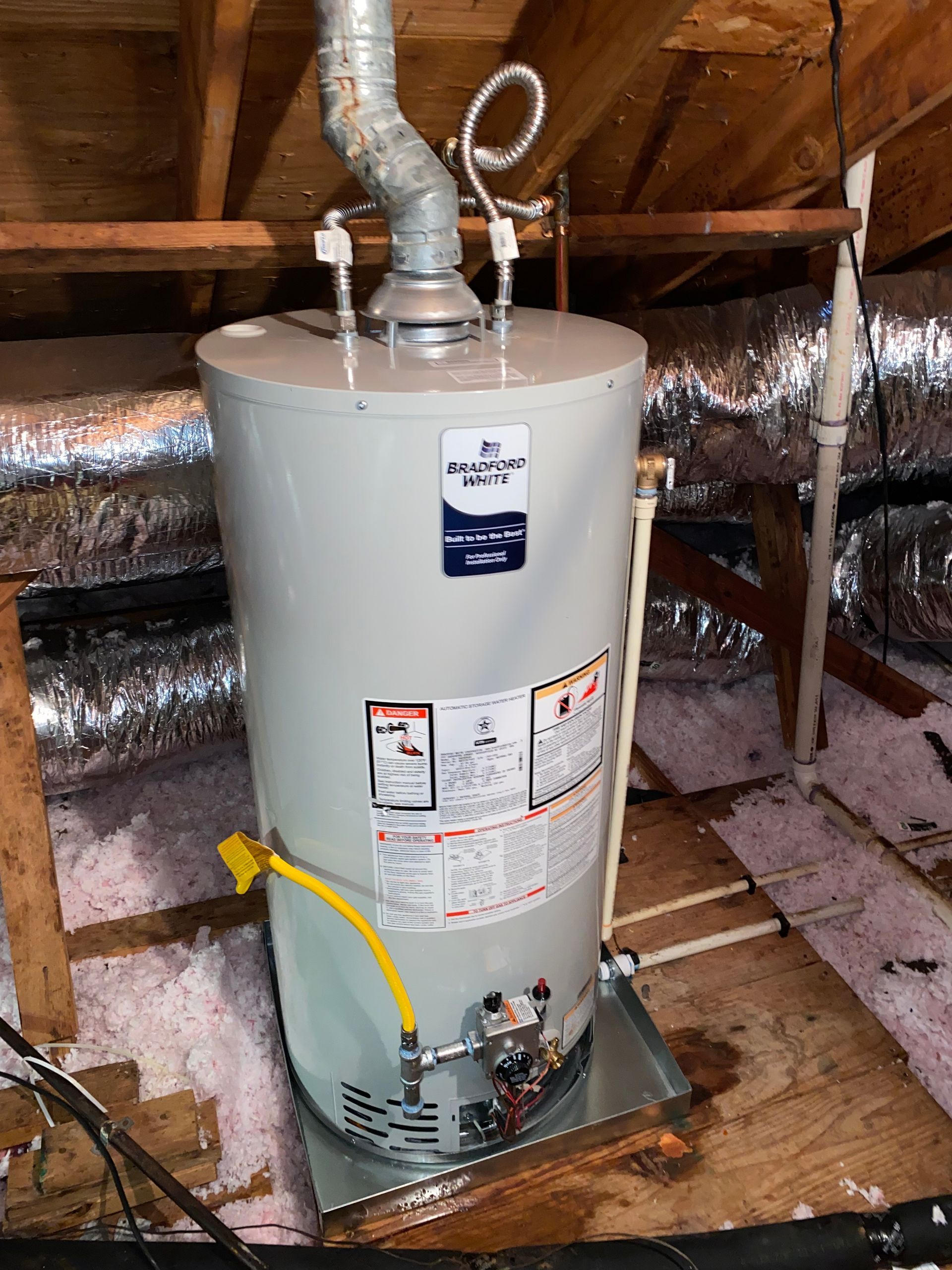 A water heater is sitting in the attic of a house.