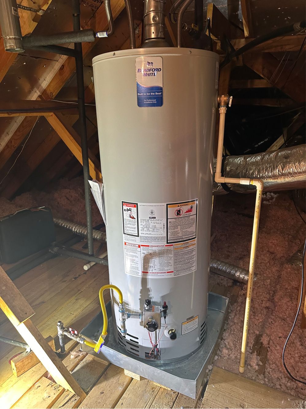 A water heater is sitting in the attic of a house.