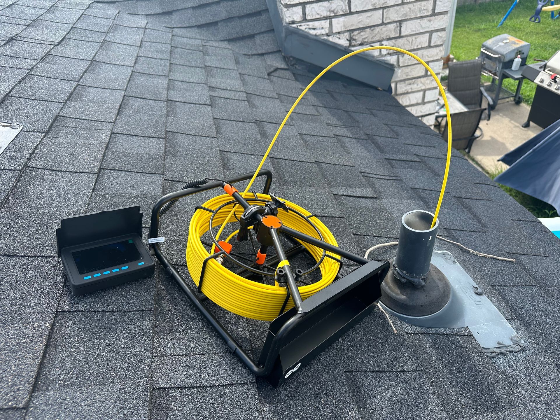 A yellow hose is sitting on top of a roof next to a camera.