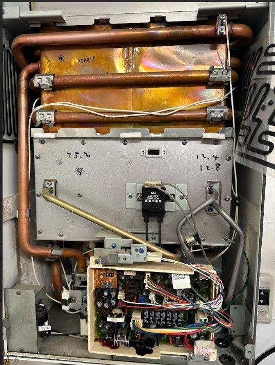 The inside of a water heater with copper pipes and wires