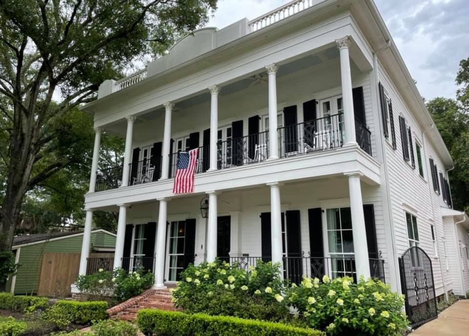 A black stepladder stands in a bright, empty room with glass partitions while a person works in the background.
