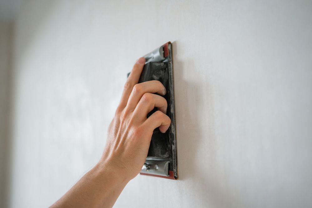 A living room with a fireplace, television, leather armchair, wooden coffee table, and an open dining area beyond.