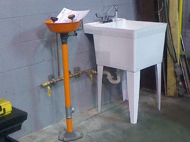 A white laundry sink is next to an orange stand
