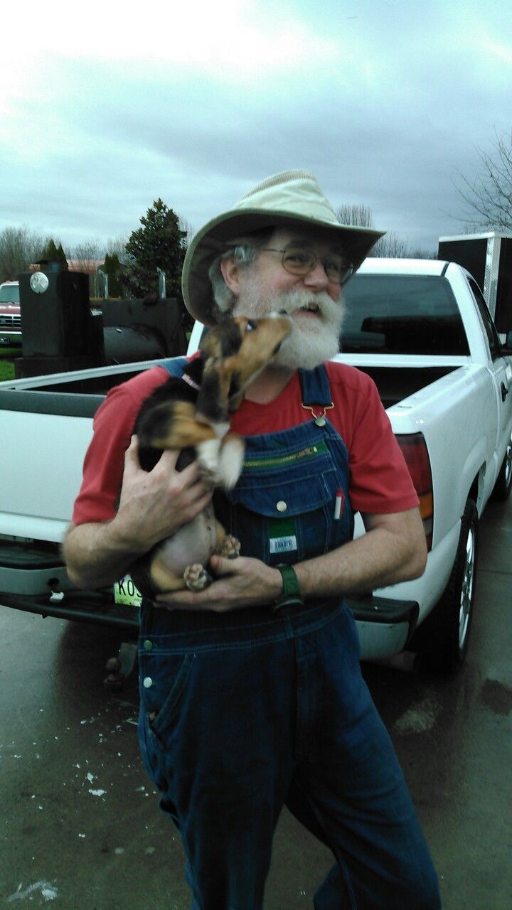 A man holding a small dog in front of a truck