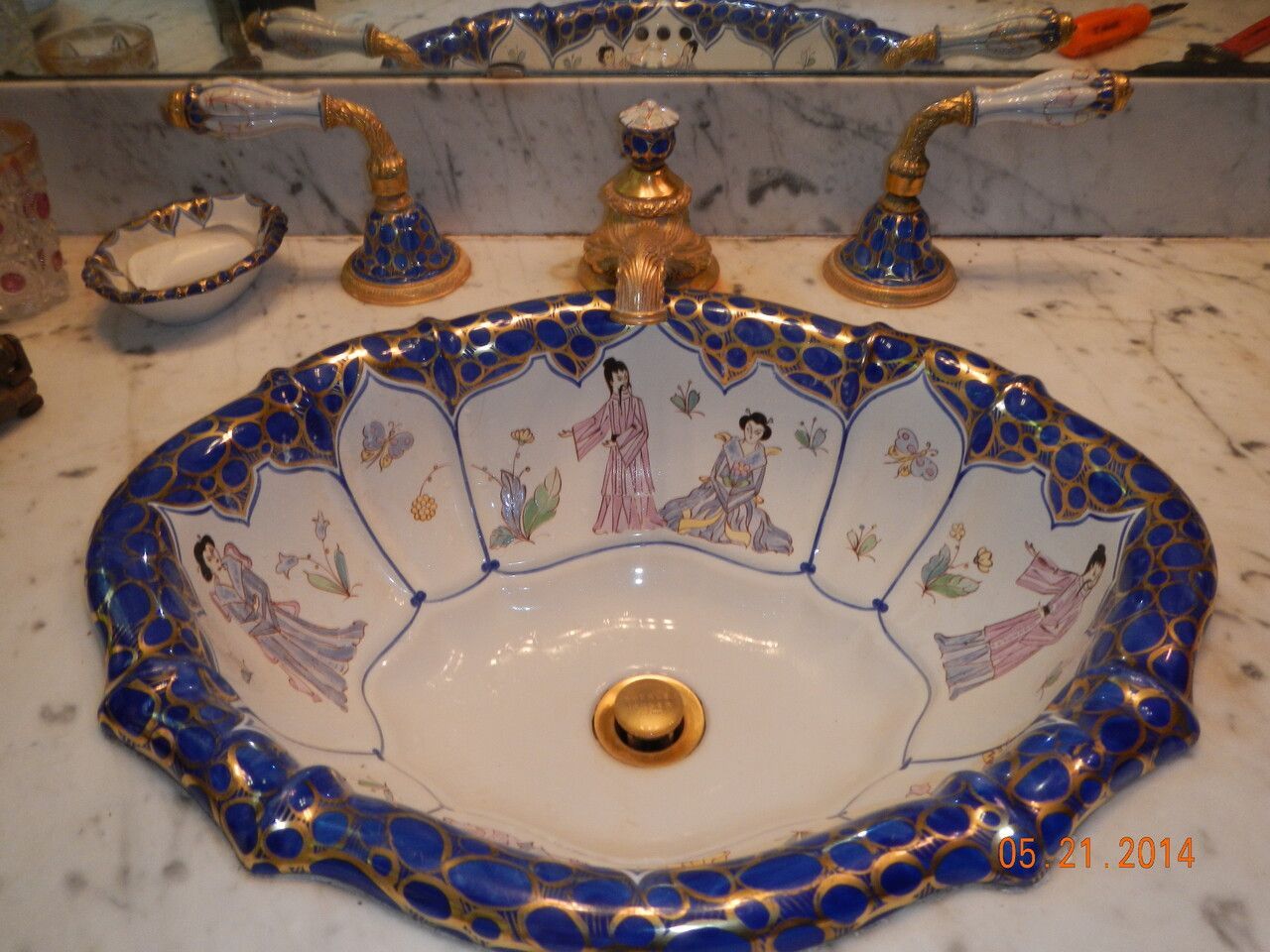 A blue and white sink with a picture of geishas on it