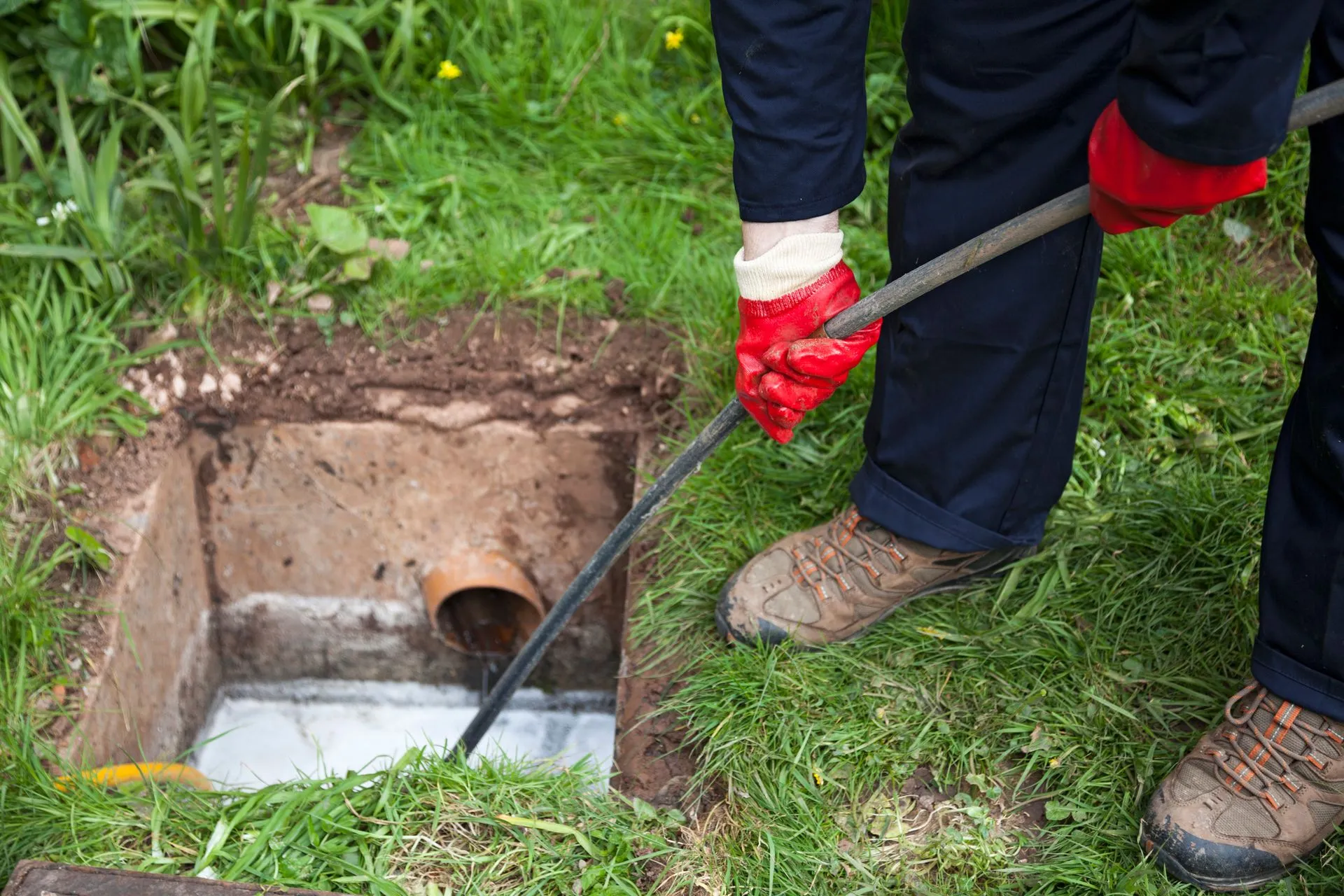 A person is cleaning a septic tank with a hose.