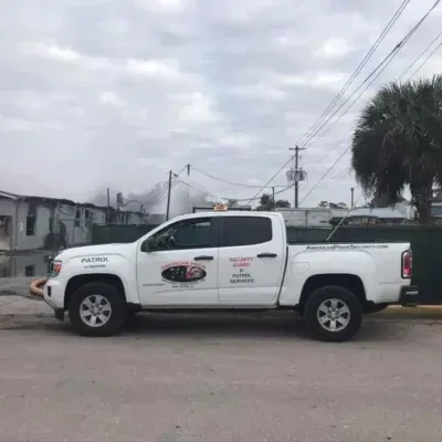 White work truck parked on a street with buildings and cloudy sky.