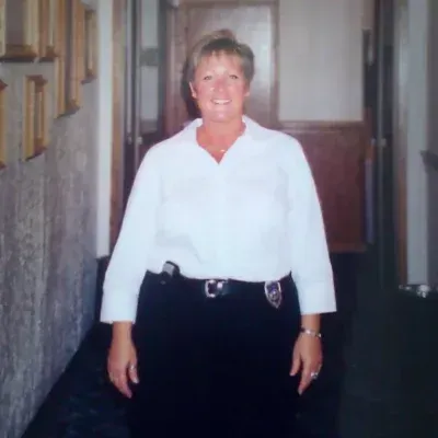 Woman in white shirt and black skirt standing in hallway.