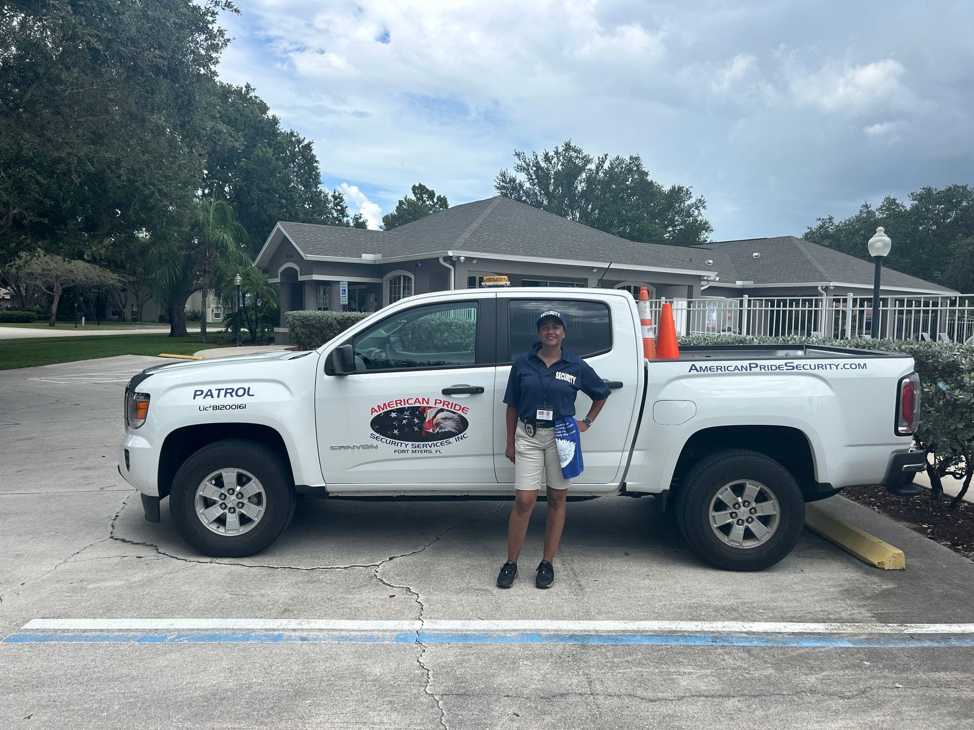 Woman standing next to white work truck with logo. Buildings and trees in the background.