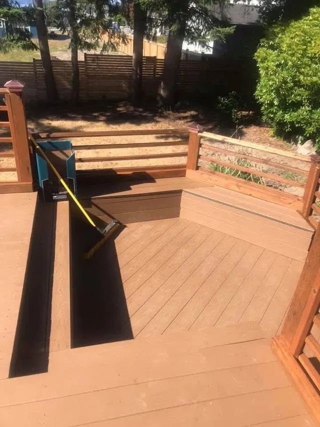 A person is measuring a wooden deck with a tape measure.