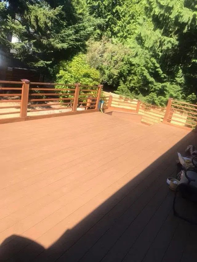 A wooden deck with a wooden railing and trees in the background.