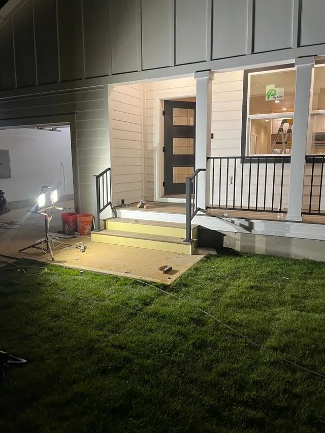 A house with a porch and stairs is being remodeled at night.