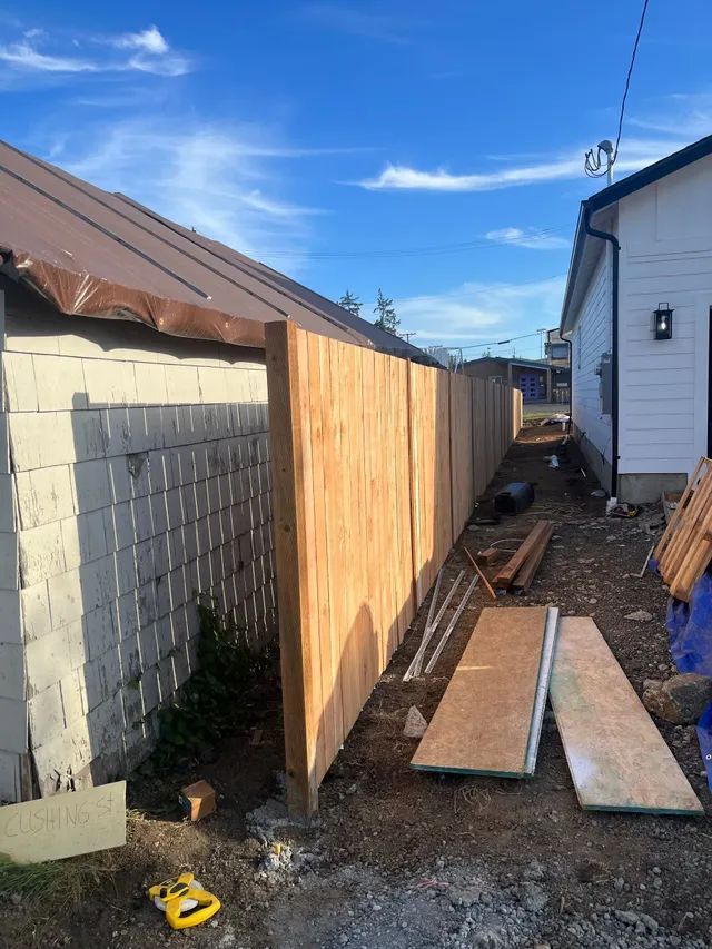 A wooden fence is being built in the backyard of a house.