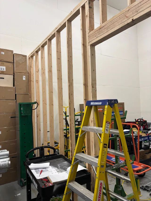 A yellow ladder is sitting in a room with boxes and carts.