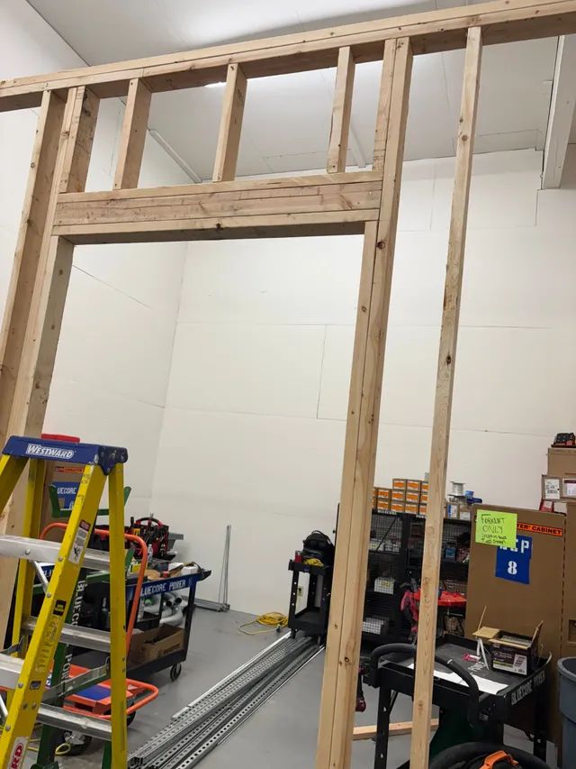 A wooden frame is being built in a room with a ladder.