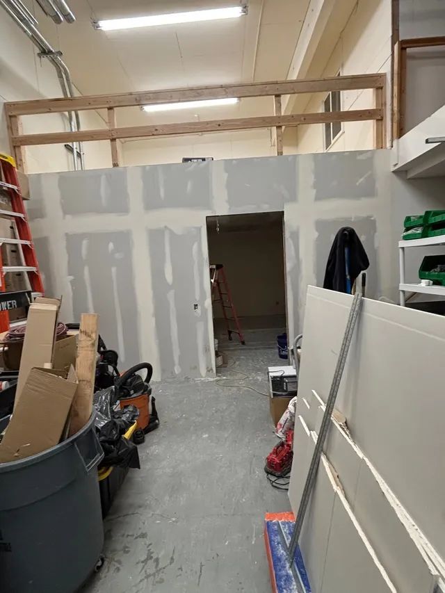 A room with drywall walls and a ladder in it.