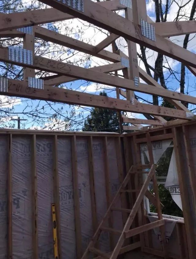 A building under construction with a ladder going up to the roof