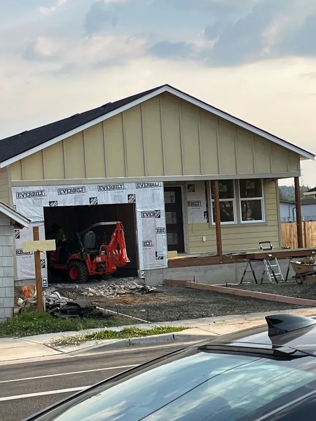 A car is parked in front of a house under construction.
