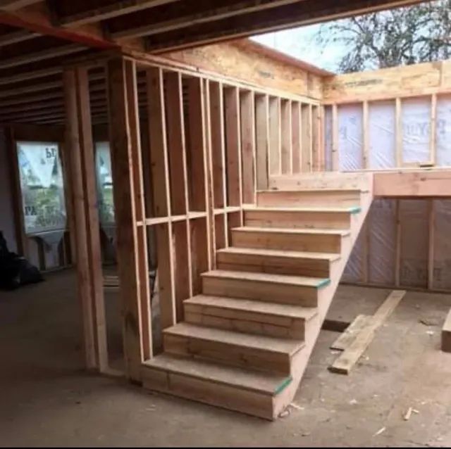 A wooden staircase is being built in a house