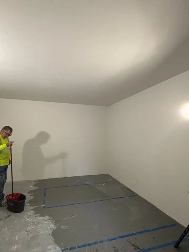 A man is standing in a room with a mop and bucket.