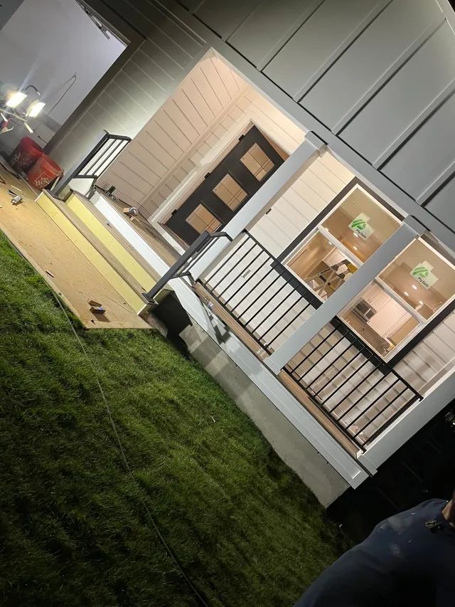 A person is standing in front of a house with a porch