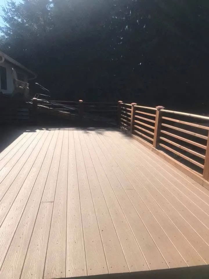 A wooden deck with a wooden railing and trees in the background.
