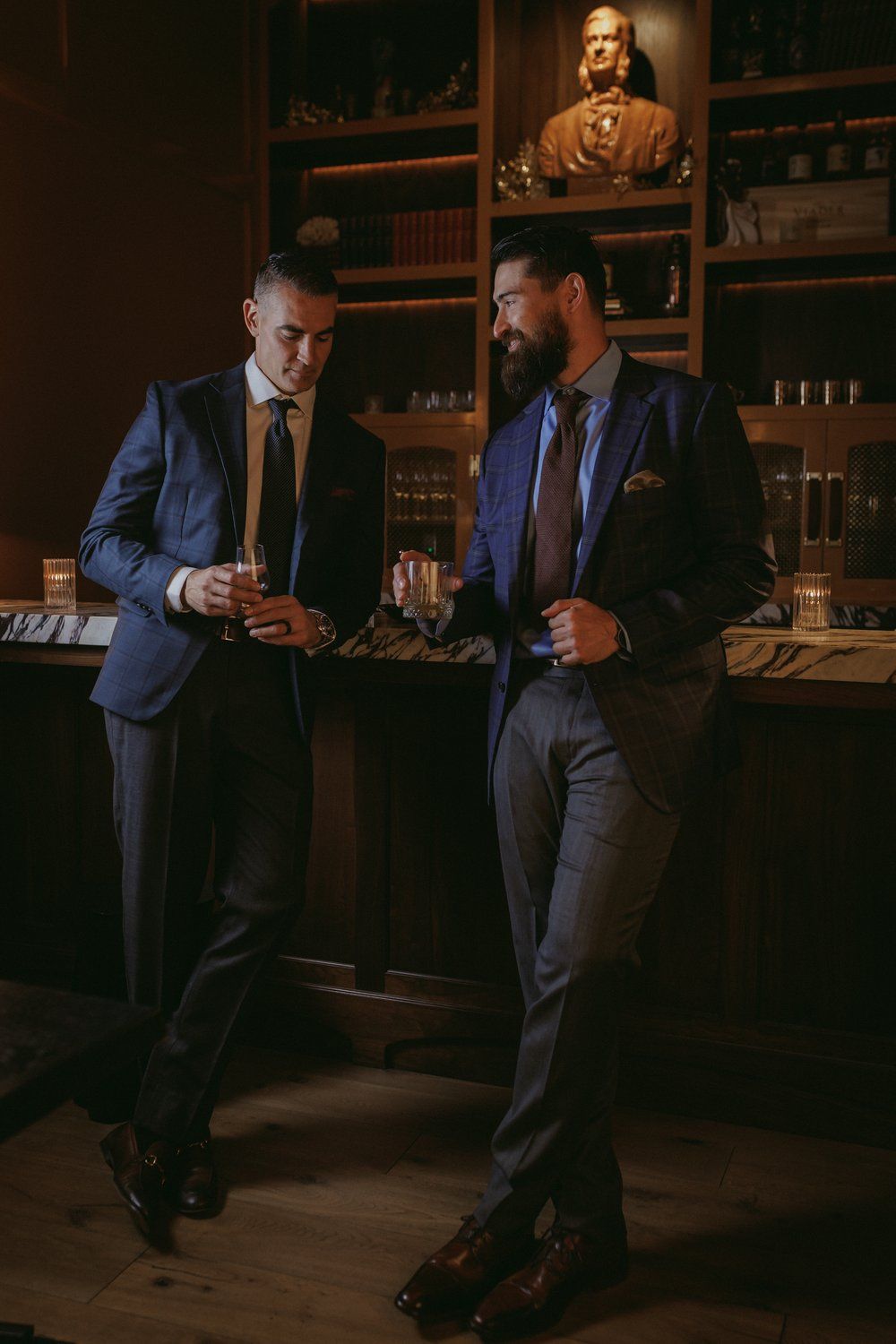 Two men in suits and ties are standing next to each other in a dark room.