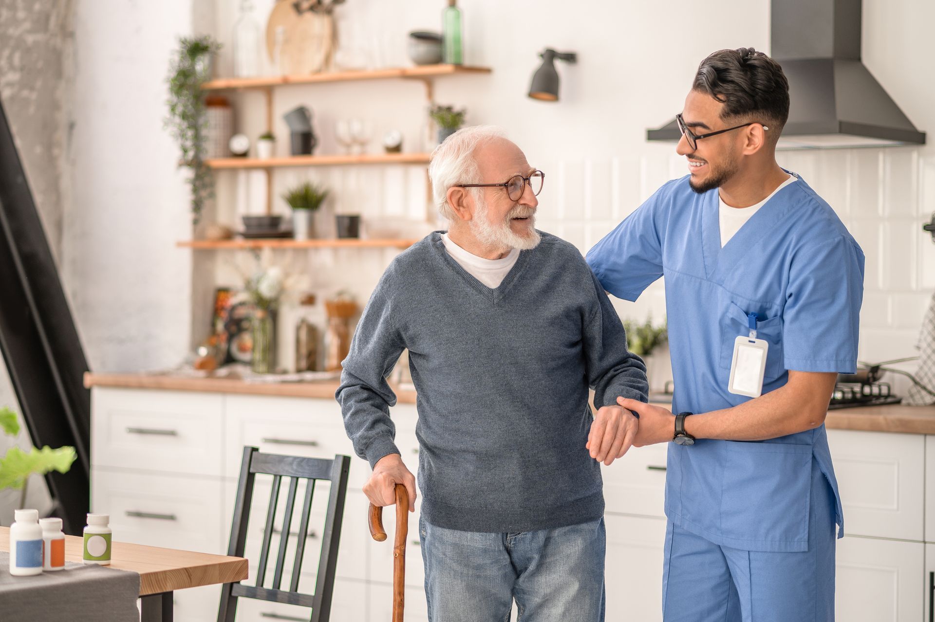 Smiling nurse supporting elderly man at home as part of professional elderly home care.