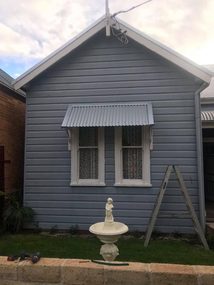 A blue house with a white fountain in front of it — Heritage Window Awnings in the Hunter Valley, NSW